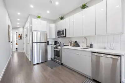 a kitchen with white cabinets and a stainless steel refrigerator at SWJ 5th - Perfect for Tourism: Near Train, Times Sq, Dining in New York