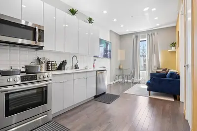 a kitchen with white cabinets and a blue couch at SWJ 5th - Perfect for Tourism: Near Train, Times Sq, Dining in New York