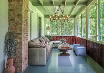 a screened in porch with a couch and a table at Luxuriously Restored Farm Cabin in Mountainhome