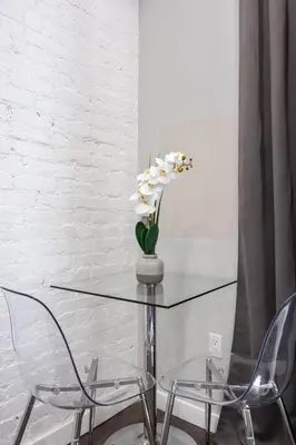 a glass table with two chairs and a vase with flowers at SWJ Btm G, 1 and 2 - Save on 2Day+ Stays_6Br Triplex in New York