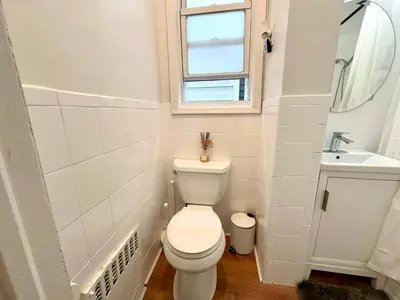 a white bathroom with a toilet and a sink at 10-A Diamond in Yonkers, NY in Yonkers
