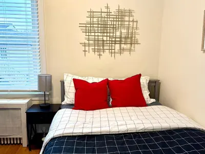 a bedroom with a bed with red pillows and a chandelier at 10-A Diamond in Yonkers, NY in Yonkers