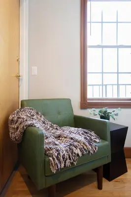 a green couch in a room with a blanket on it at Downtown New Haven, Spacious Stay by Yale - AO Destinations in New Haven