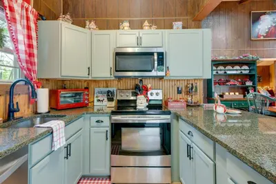 a kitchen with white cabinets and a stove top oven at 1 Mi to Gouldsboro State Park Cabin with Deck! in Gouldsboro