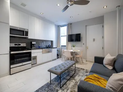 a living room with a blue couch and a kitchen at Cozy & Convenient Midtown Condo-Hotel! in New York