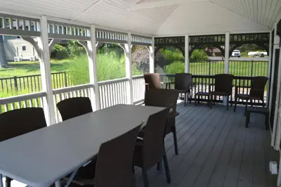 a covered porch with tables and chairs and a view at Woodfield Manor - A Sundance Vacations Property in Cresco