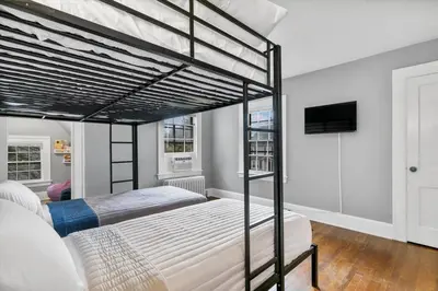 a bedroom with two bunk beds and a flat screen tv at Quintessential Cozy Haven, Brooklawn Beauty in Bridgeport