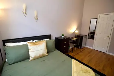 a bedroom with a bed with green sheets and a mirror at Tuk Ahoy - Emerald Suite 2C with Shared Spaces in Brooklyn