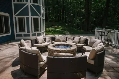 a patio with a couch and chairs and a fire pit at The Athena Hideaway - hottub, firepit, lake & racetrack in Saratoga Springs