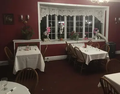 a dining room with two tables and a window at The Tunnicliff Inn in Cooperstown