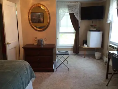a bedroom with a mirror and a dresser and a window at The Tunnicliff Inn in Cooperstown