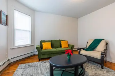 a living room with a green couch and a table at Frog Hollow Red Door Haven in Hartford