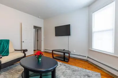 a living room with a couch and a table and a tv at Frog Hollow Red Door Haven in Hartford