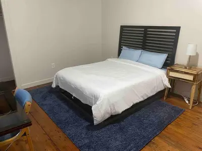a bedroom with a large bed with a blue rug at Frog Hollow Red Door Haven in Hartford