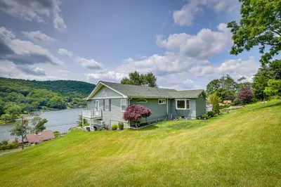 a house on a grassy hill with a lake at New Fairfield Vacation Rental with Lake Views! in New Fairfield