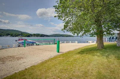 a beach with a tree and a boat in the water at New Fairfield Vacation Rental with Lake Views! in New Fairfield