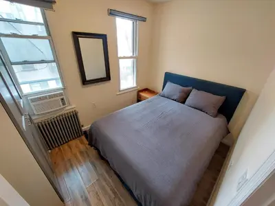 a small bedroom with a bed and a window at Comfortable Apartment with Workstation in New York