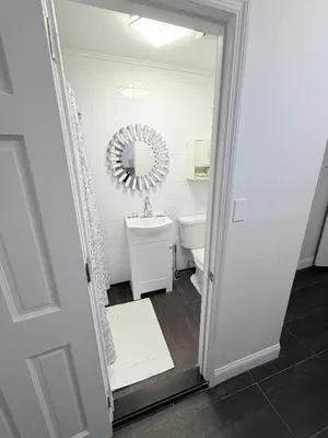 a white bathroom with a sink and a mirror at Comfortable 2BR & 2 Bath Apt in Downtown NYC in New York