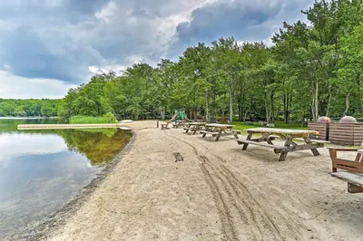 a row of picnic tables on the shore of a lake at Deck, Fire Pit and Sauna Big Bass Lake Getaway! in Clifton