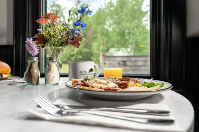 a plate of pizza sitting on a table with a window at Hotel Mountain Brook in Tannersville