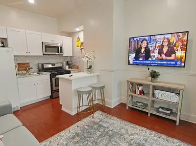 a living room with a kitchen with a tv on the wall at Elegant 3Br Apt Yankee stadium in Melrose