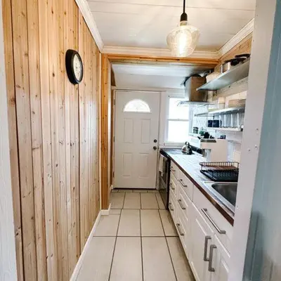 a kitchen with wooden walls and a clock on the wall at Historic peaceful apartment in New Haven