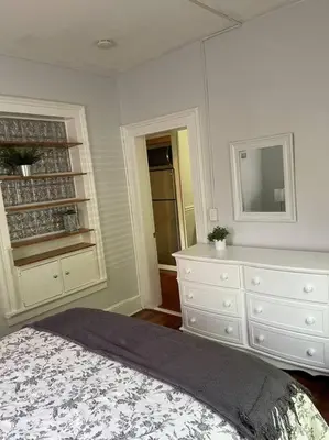 a white bedroom with a bed and a dresser at Historic peaceful apartment in New Haven