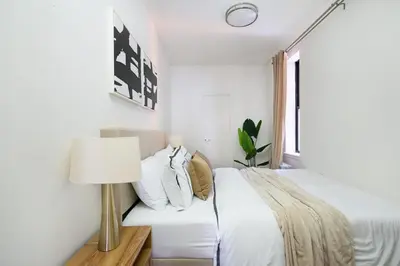 a white bedroom with a bed and a lamp at 1288-3RN New Renovated 1 Bedroom in UES in New York