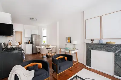a living room with two chairs and a kitchen at 1288-3RN New Renovated 1 Bedroom in UES in New York