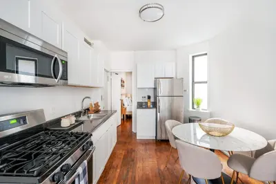 a kitchen with white cabinets and a table with chairs at 1288-3RN New Renovated 1 Bedroom in UES in New York