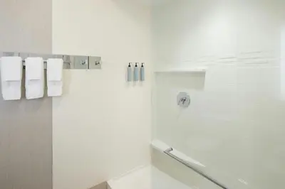 a white bathroom with a shower with white towels at Residence Inn by Marriott Albany Clifton Park in Clifton Park