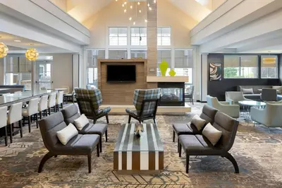 a hotel lobby with chairs and a bar at Residence Inn by Marriott Albany Clifton Park in Clifton Park