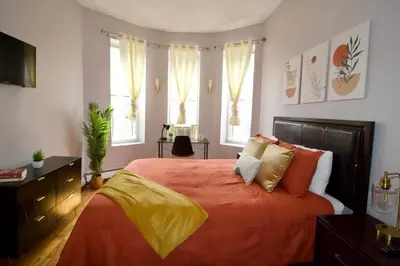 a bedroom with a bed with orange sheets and pillows at Tuk Ahoy - Sunset Suite 2B with Shared Spaces in Brooklyn