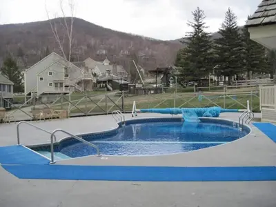 a pool in a yard with a blue pool at 1st Floor Mountain View Suite Ski On Off At Jiminy- Fully Redone Decor in Hancock