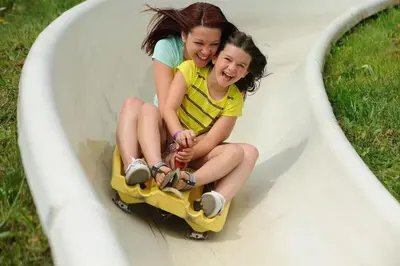 two young girls riding on a roller coaster at 1st Floor Mountain View Suite Ski On Off At Jiminy- Fully Redone Decor in Hancock