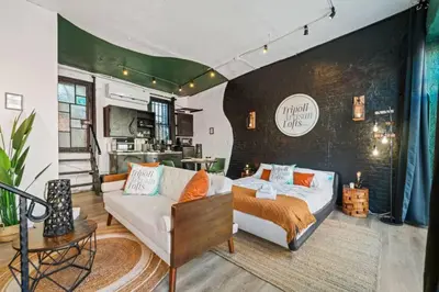 a living room with a couch and a kitchen at Tripoli Artisan Lofts - Designer Bushwick Lofts with Rooftop Terrace in Brooklyn
