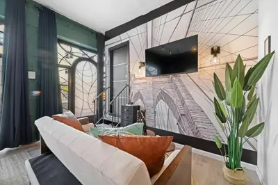 a living room with a couch and a tv on a wall at Tripoli Artisan Lofts - Designer Bushwick Lofts with Rooftop Terrace in Brooklyn