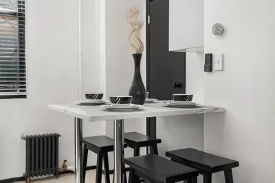 a white table with stools and a vase on it at Tripoli Artisan Lofts - Designer Bushwick Lofts with Rooftop Terrace in Brooklyn