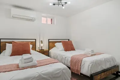 two beds in a room with white walls at Tripoli Artisan Lofts - Designer Bushwick Lofts with Rooftop Terrace in Brooklyn