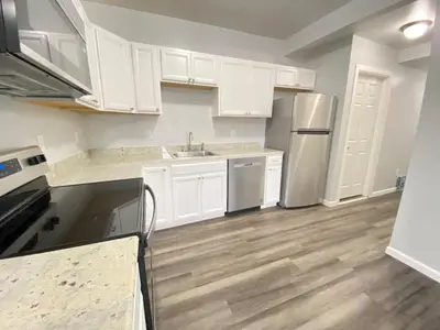 a kitchen with white cabinets and a sink and refrigerator at 3rd Base Apt 1 All Star Baseball Rentals in Oneonta
