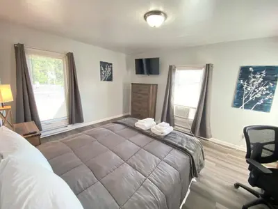 a bedroom with a bed and a chair and windows at 3rd Base Apt 2 All Star Baseball Rentals in Oneonta