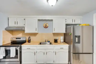 a kitchen with white cabinets and a stainless steel refrigerator at Cozy Albany Vacation Rental about 5 Mi to Downtown! in Albany