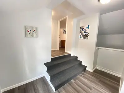 a staircase in a home with white walls and wood floors at Double Play Apt 1 All Star Baseball Rentals in Oneonta