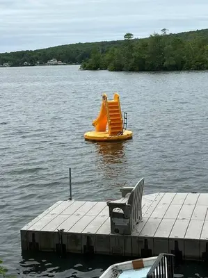 a dock with a yellow inflatable slide on a lake at Fun on the Lake in East Hampton