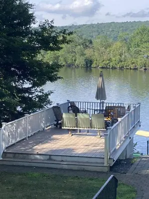a wooden deck with chairs and an umbrella on a lake at Fun on the Lake in East Hampton
