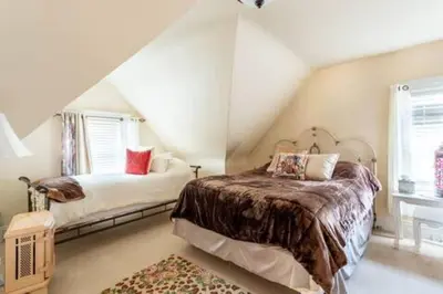 a attic bedroom with two beds and a window at Large Space Great for Groups & Families in Montclair