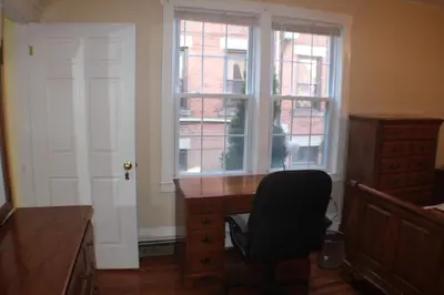 a desk and a chair in a room with a window at West End Haven in Hartford