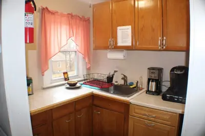 a kitchen with wooden cabinets and a sink and a window at West End Haven in Hartford