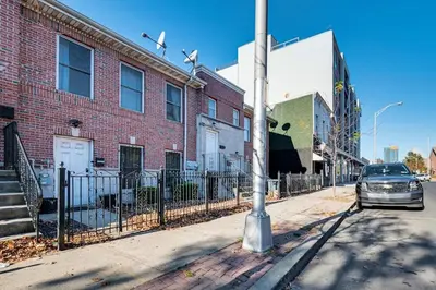a car parked on a street next to a brick building at 3br private Apartment in Jersey City