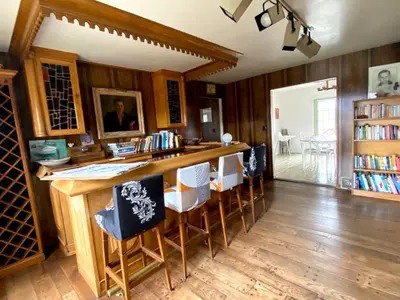 a kitchen with a bar with chairs and books at Daydream Mountain Art Chateau in Catskill